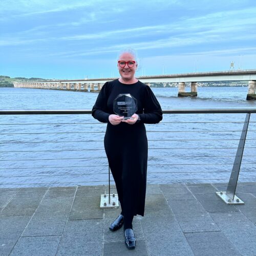 Scotland's Library and Information Professional of the year 2024, Alison Nolan holding her award at the Dundee waterside.