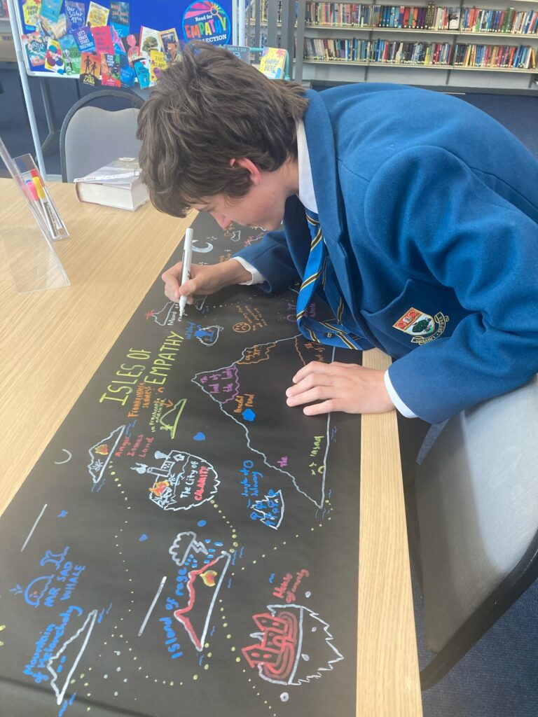 A school pupil drawing a multicoloured chalk Isles of Empathy illustration for Empathy Day.