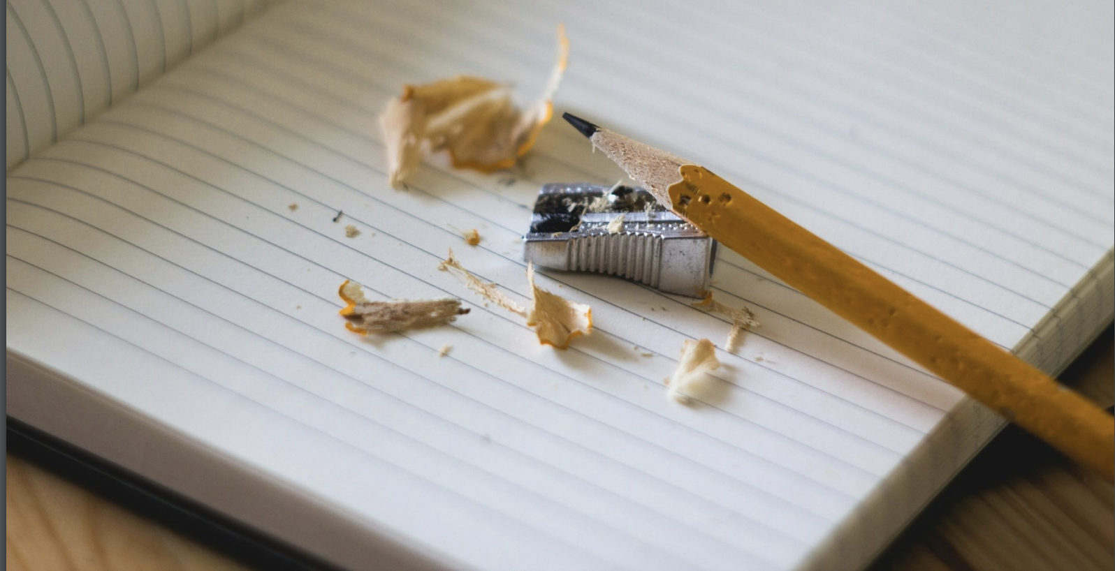 Image of pencil being sharpened on top of lined paper.